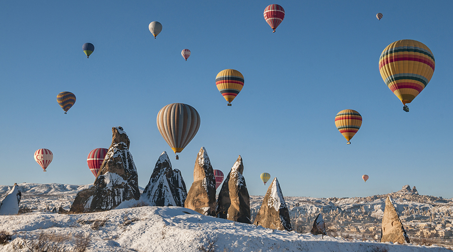 A group of hot air balloons flying over a mountain; image used for HSBC Malaysia 7 great year-end holiday destinations article