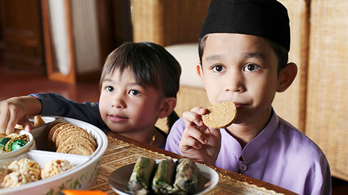 Find out more about Two children are eating snacks at a table; image used for HSBC Malaysia Best Ramadan Bazaars article