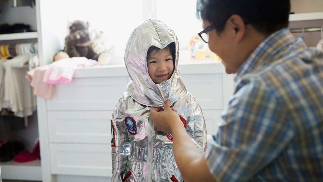 Boy put on coat by father; image used for HSBC Malaysia Accounts Savings page.