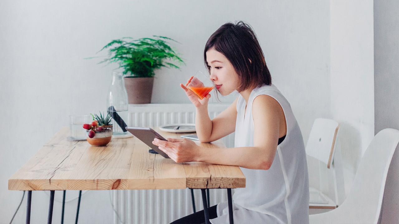 A woman using a tablet while drinking; image used for HSBC Malaysia faq page