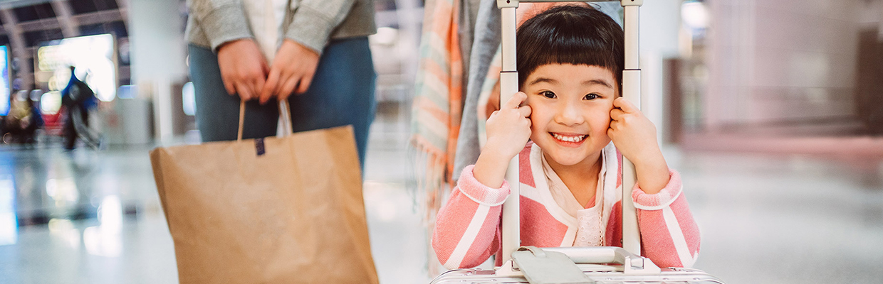 A little girl smiling with a suitcase; image used for HSBC Malaysia Visa Signature Credit Card