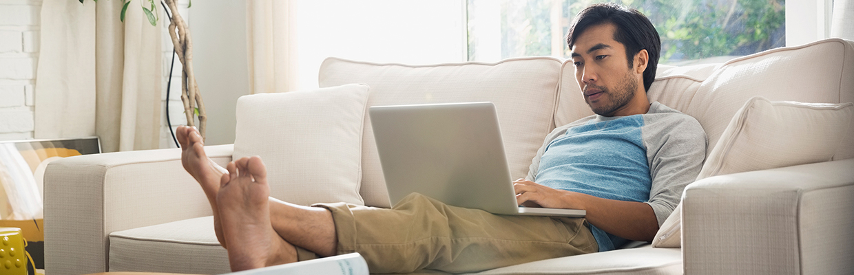 A man is working on his laptop at home; image used for HSBC Foreign Currency Account page.