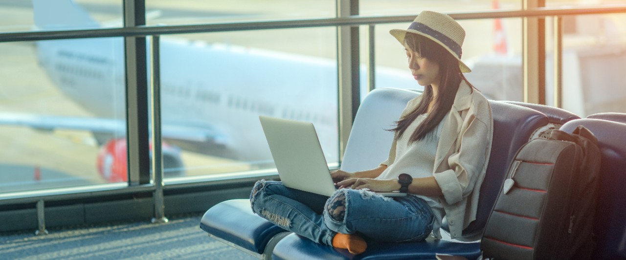 A woman is using her laptop in an airport; image used for HSBC Malaysia Premier Study Abroad article