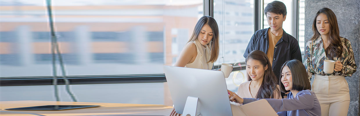 4 girls and 1 guy are looking at the monitor together in an office room; image used for HSBC Malaysia comparison account saving page. 