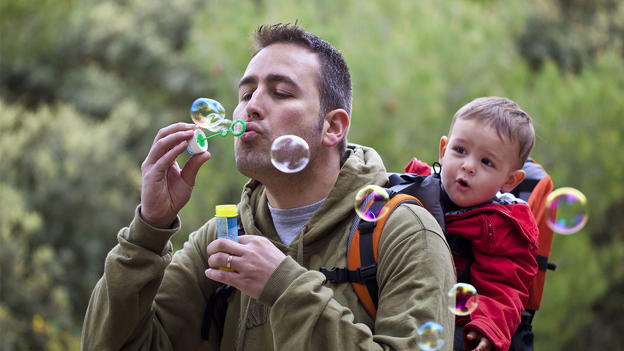 A dad is playing blow bubble wiht his kid; image used on HSBC Malaysia Fast access more control page.