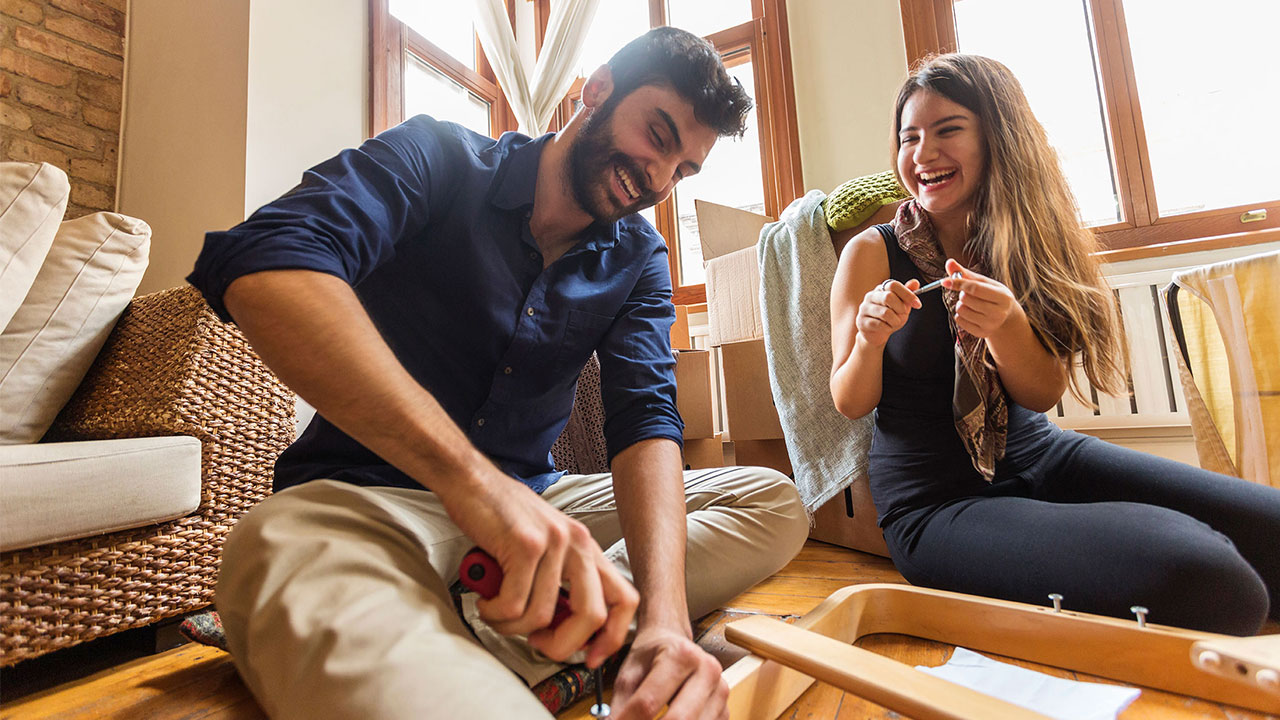 A man and woman are are laughing together while building furniture; image used on HSBC Malaysia Online and on your side page.