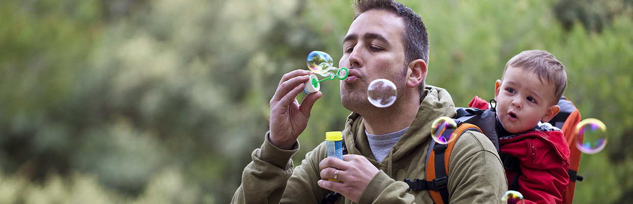 A dad is playing blow bubble wiht his kid; image used on HSBC Malaysia Fast access more control page.