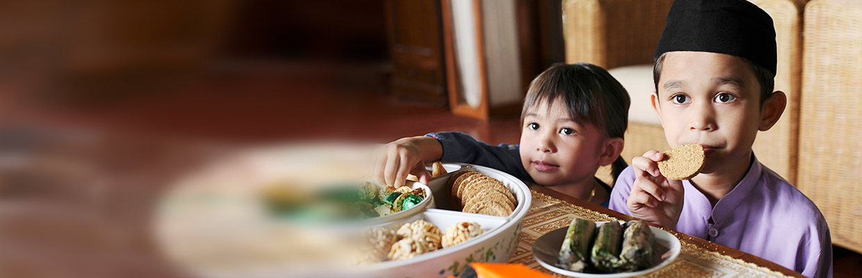 A boy and a girl are eating snacks at a table; image used for HSBC Malaysia Ramadan Dining campaign