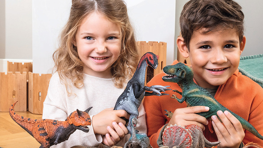A girl and a boy are playing dinosaur toys together
