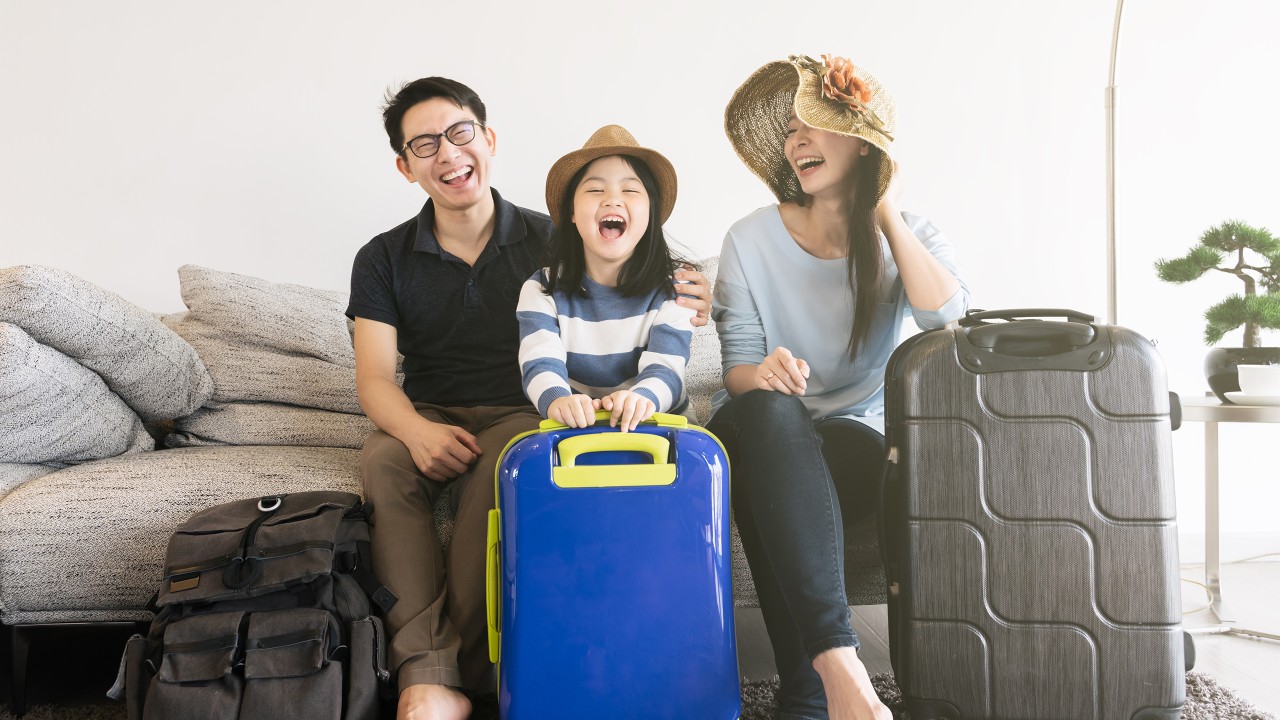 Parents and daughter are having their luggage next to them happily, image used for HSBC Malaysia Mastercard travel reward page.