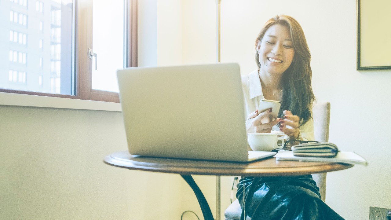 A lady is using mobile and laptop; image used for HSBC Malaysia saving vs investing article page.