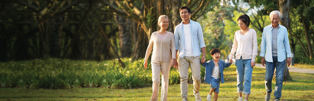 A family of five, the grandma, grandpa, mom, dad, and son, are strolling in a park; image used for HSBC FamilyCare Plan page