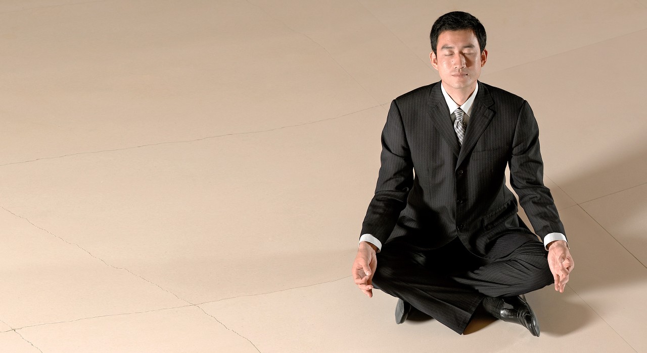 A man in a suit is meditating; image used for HSBC Malaysia Financial health and its effect on your physical well-being article page.