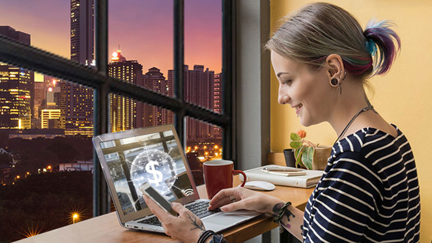 A woman holding a mobile phone and working at the computer; image used for HSBC Malaysia Dual Currency Investment