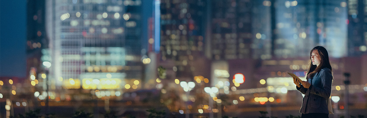 A woman is using a tablet at night; image used for HSBC Malaysia Dual Currency Investment