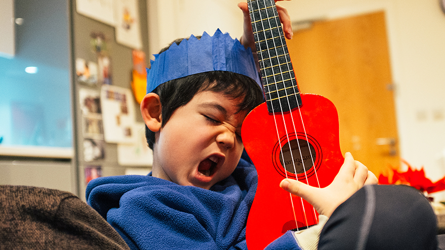 A child is playing a guitar; image used for HSBC Malaysia How to Spend Money Wisely article