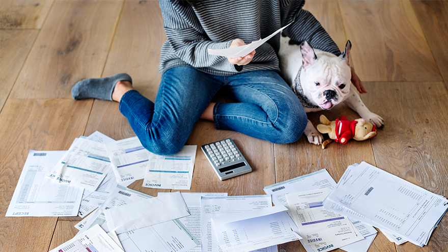 A woman is looking a bills and holding her dog; image used for HSBC Malaysia How to Spend Money Wisely article