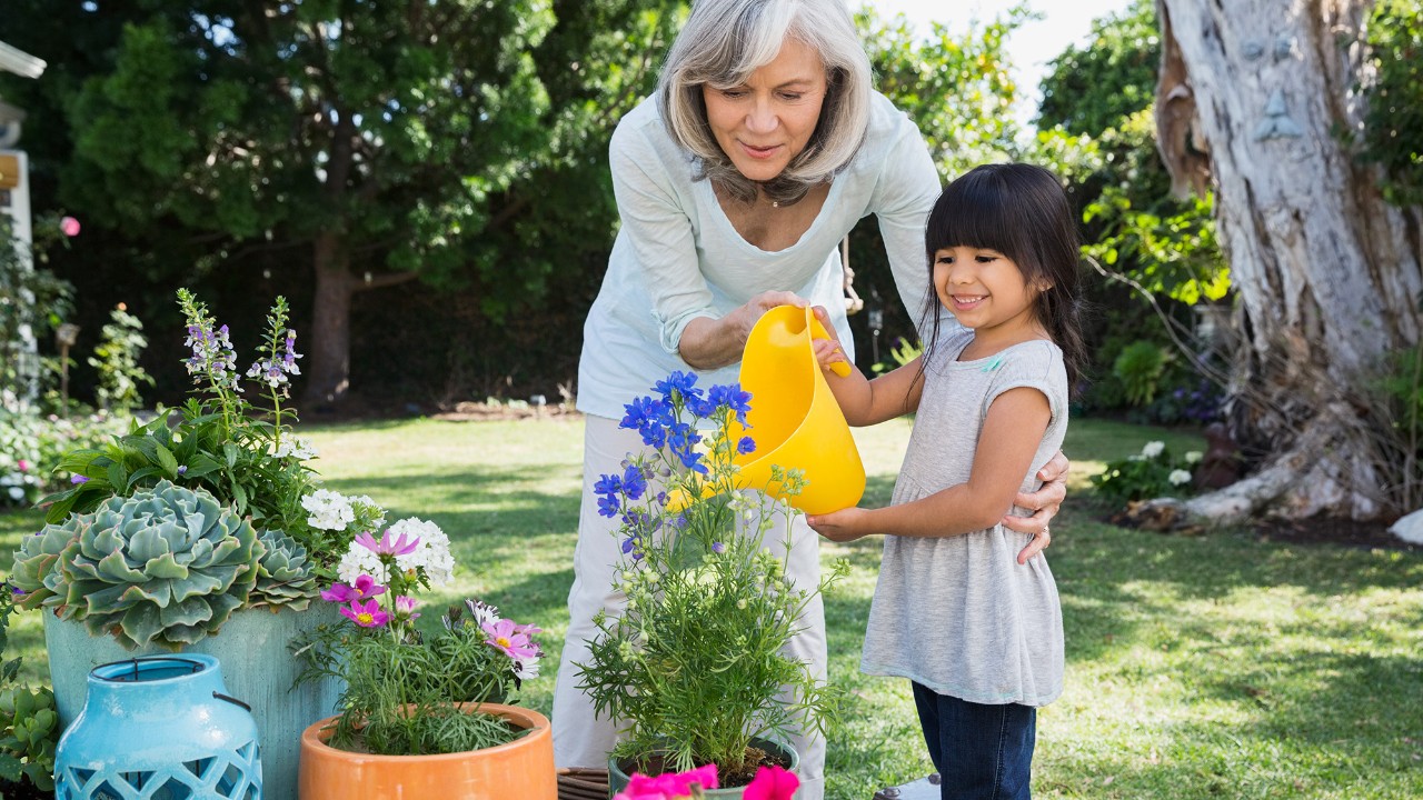 A grandmother and granddaughter are watering flowers; image used for HSBC Malaysia Second Home Mortgage