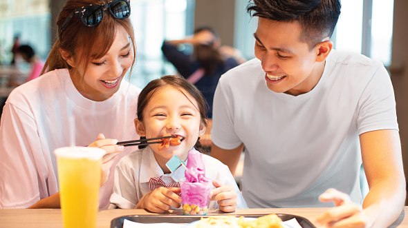 A father watches his wife feeding their daughter; image used for HSBC Malaysia credit card cash back offer