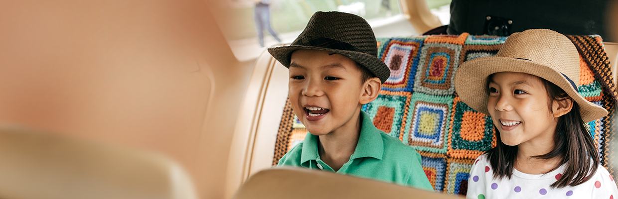Two smiling children in a car, image used by HSBC Malaysia credit cards travel offer