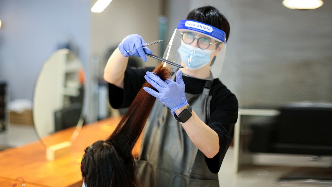 A hairdresser is wearing mask and doing haircut for his customer; image used for HSBC Malaysia Fusion ‘7 key questions you should ask before developing a post-COVID-19 business strategy ’ article.
