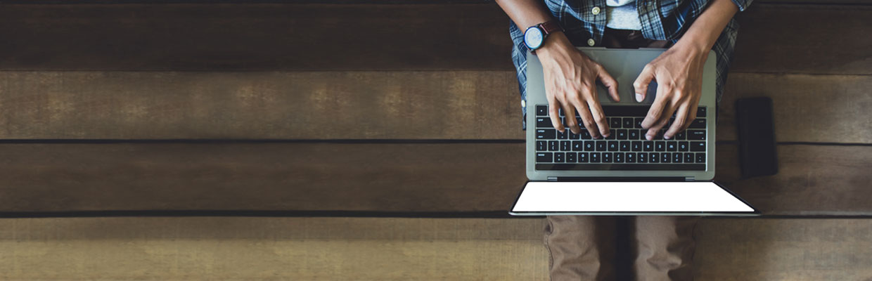 Man in casual wear typing on a laptop; image used for HSBC Malaysia Fusion ‘How SME owners protect the business from phishing’ article.