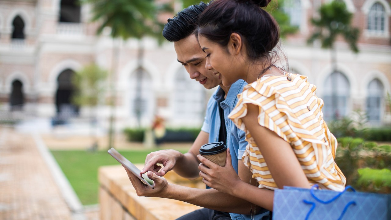 A couple are looking at a phone; image used for HSBC Malaysia Mobile Banking page