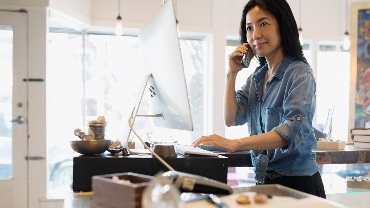 A woman is using a computer and talking on the phone; image used for HSBC Malaysia telebanking